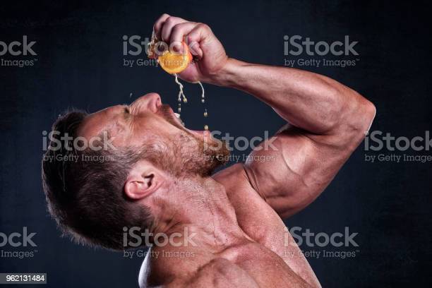muscular-man-with-orange-fruit-picture-id962131484